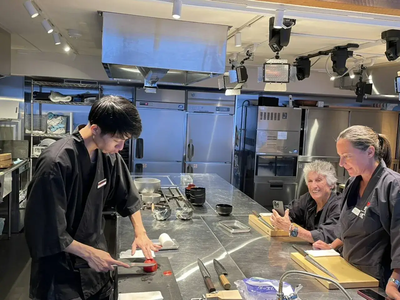 Chef enseña a dos mujeres a aprender a hacer sushi en una cocina profesional.