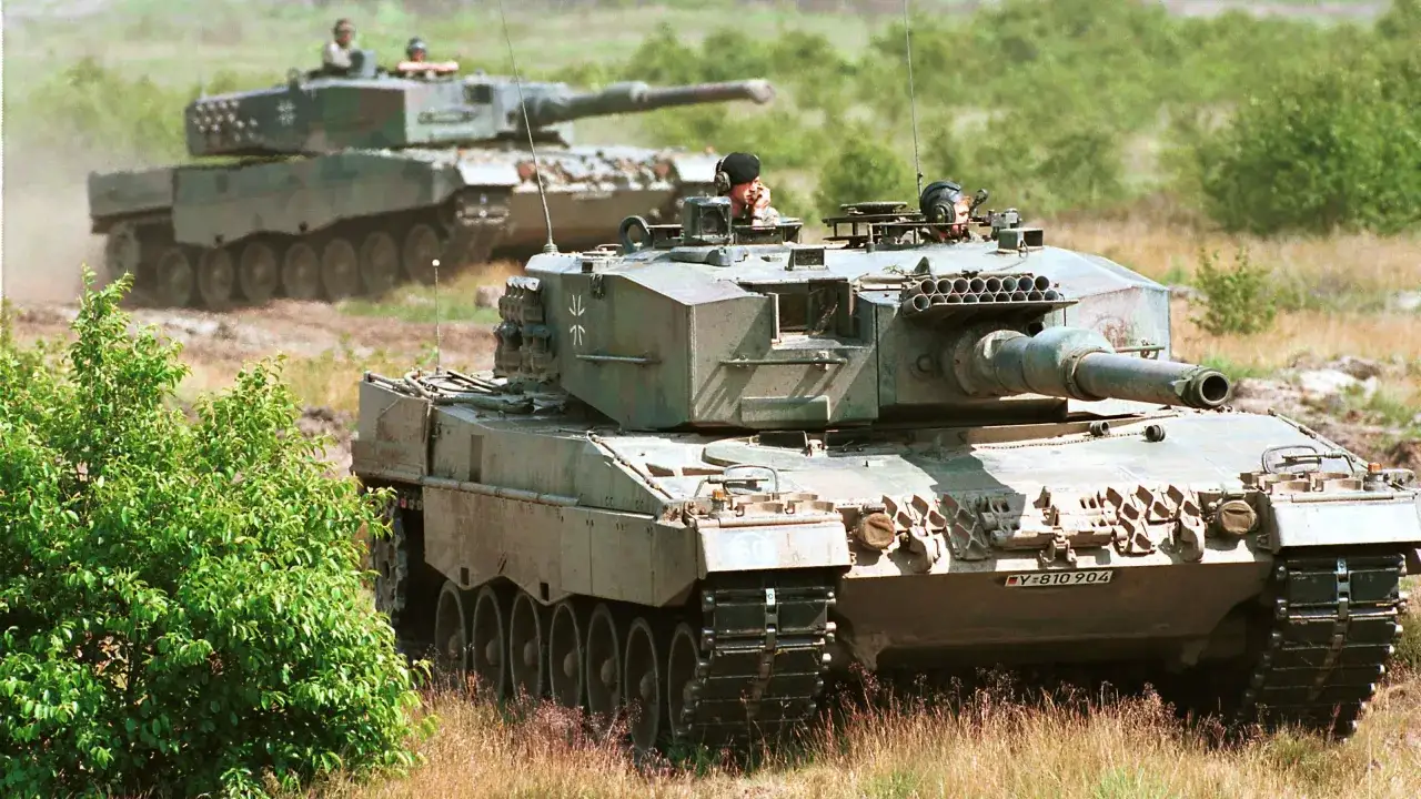 Zwei Leopard 1 Panzer fahren durch unwegsames Gel&auml;nde. Der vordere Panzer ist nah und zeigt seine Besatzung.