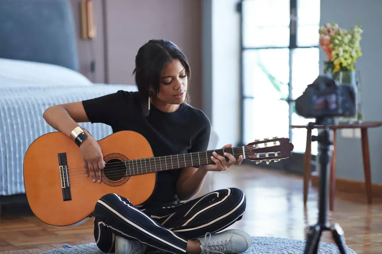 A young woman plays guitar for her online audience, a prime example of music influencer marketing.