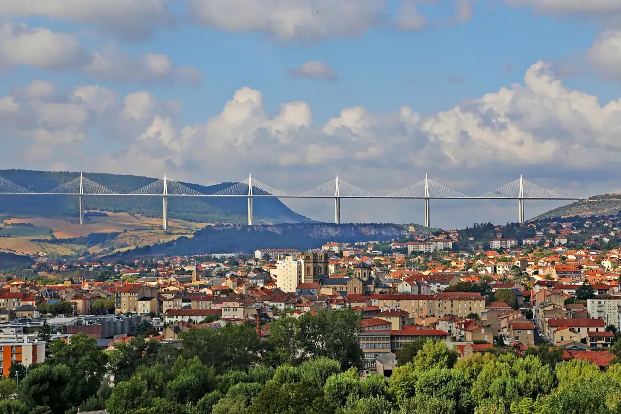 Widok na miasto z górami w tle, nad którym góruje najwyższy most w Europie.