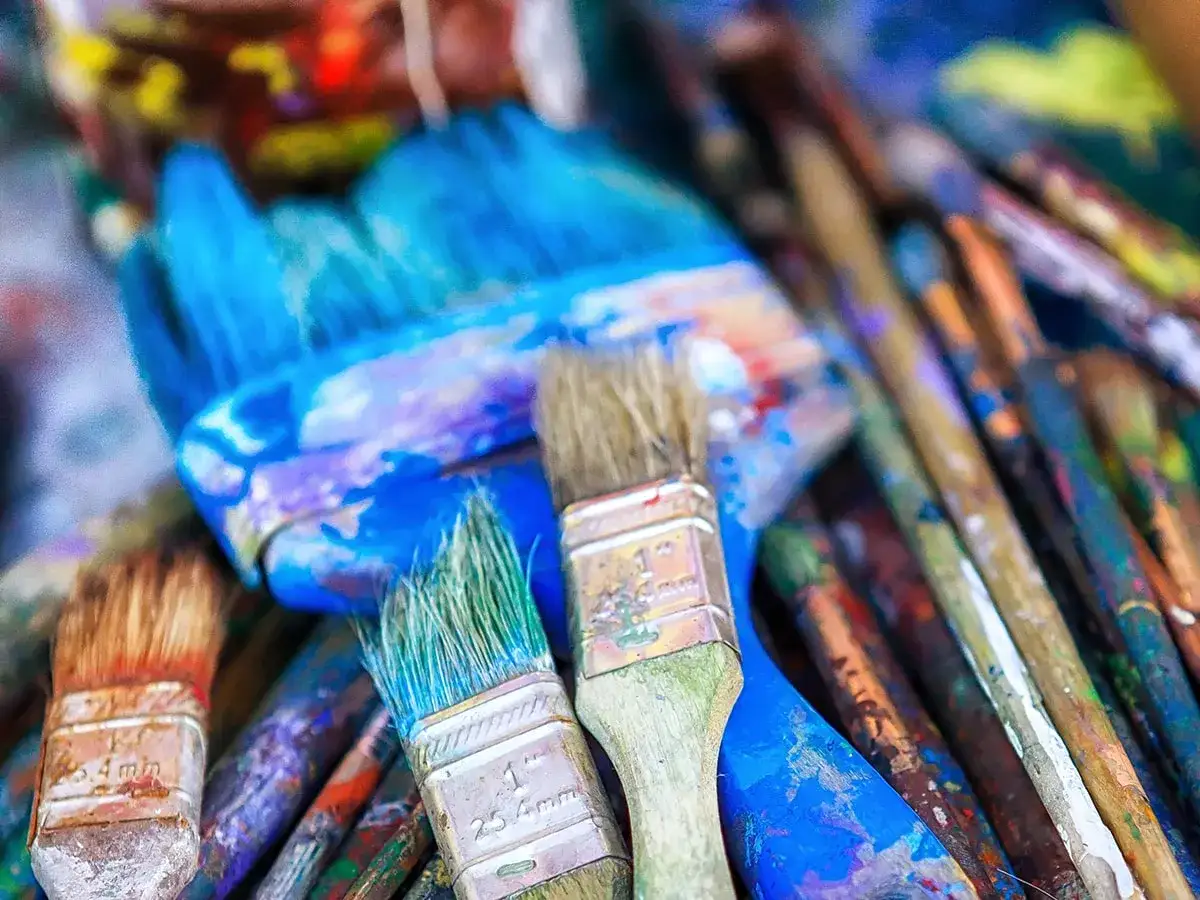 Un gros plan sur des pinceaux de peinture acrylique, certains encore couverts de couleurs vives, prêts pour un nettoyage.