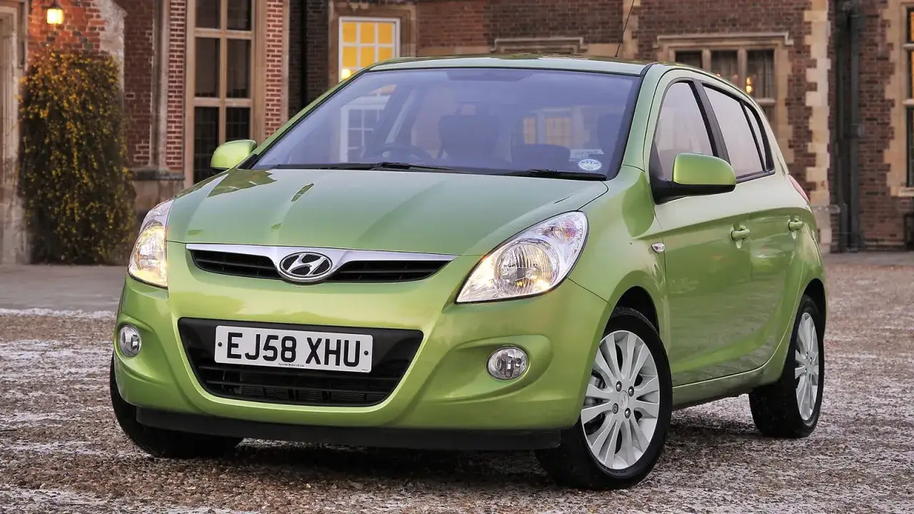 Zielony Hyundai i20 przed zabytkowym budynkiem. Czas na wymianę żarówki mijania w tym modelu.