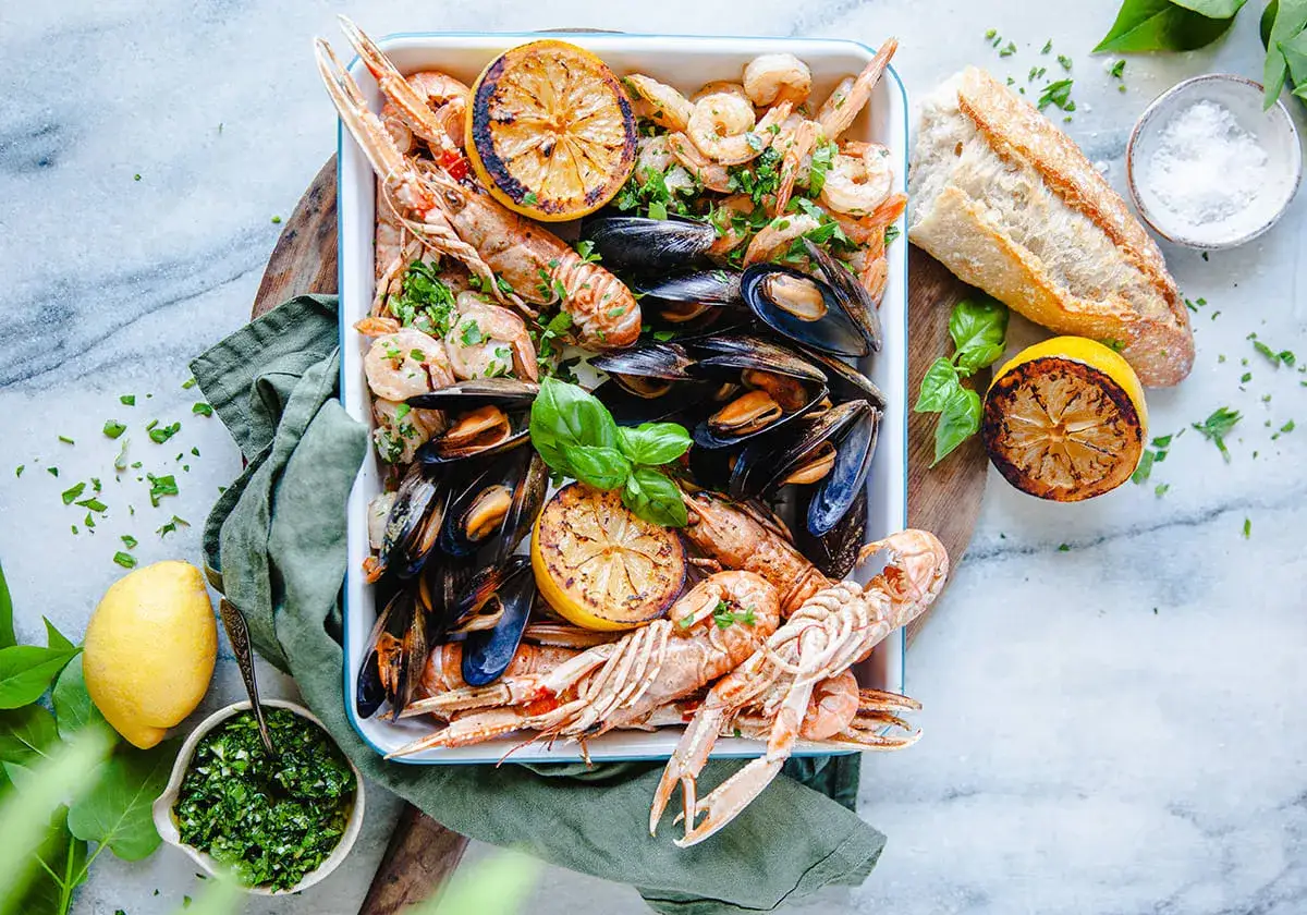 En härlig seafood boil med räkor, havskräftor och musslor, garnerad med citron och färska örter. Perfekt för en festlig middag.