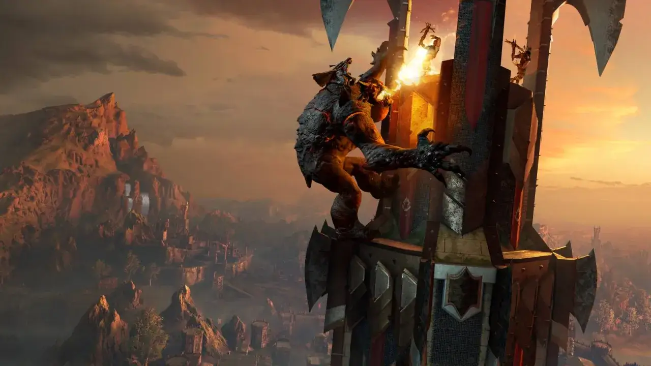 Potężny troll wspina się na wieżę, plując ogniem. W tle widać górzysty krajobraz i miasto, zapowiadające **shadow of war**.