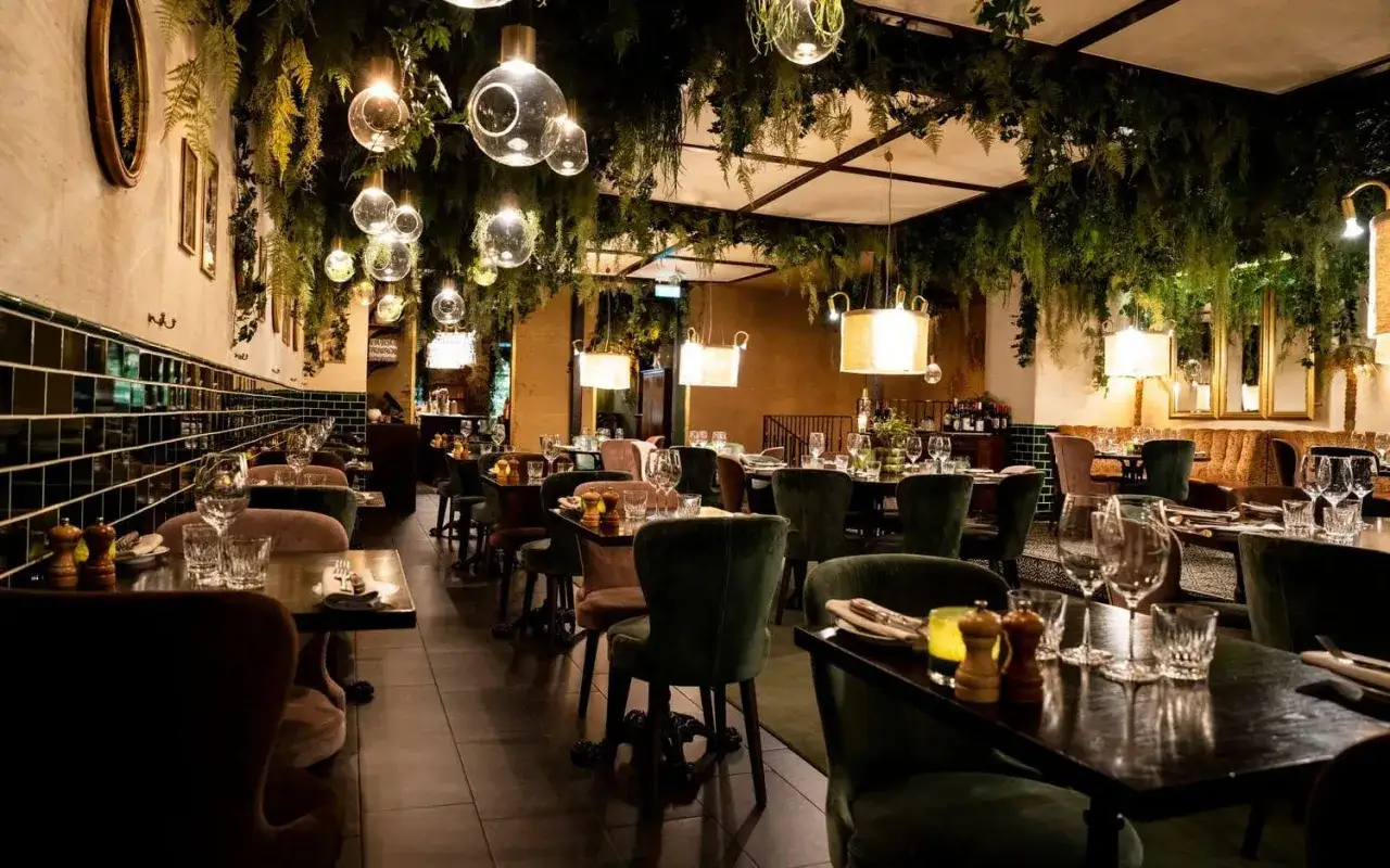 Elegant restaurang med grönska i taket och dämpad belysning. Perfekt för en mysig middag på prime grill.