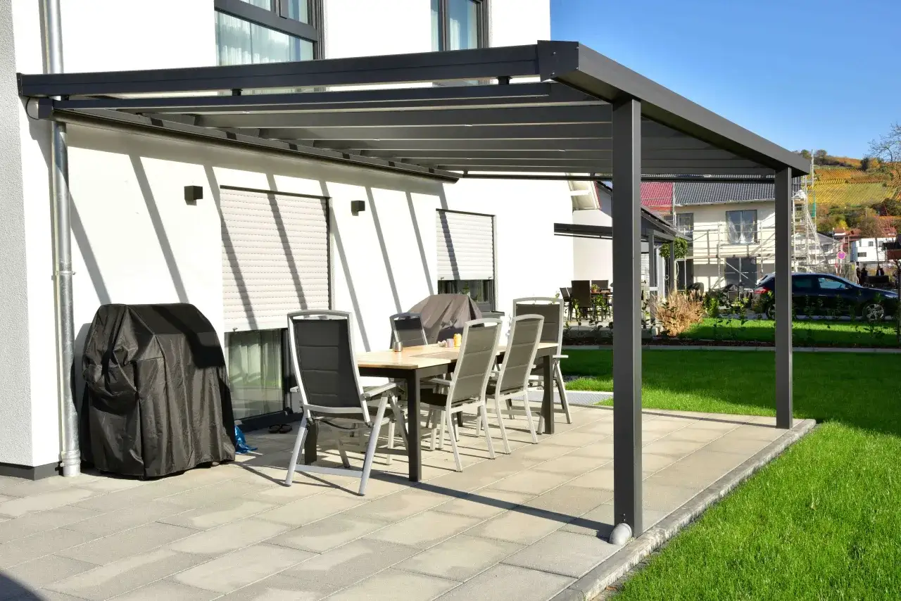 Nowoczesna pergola z miejscem do siedzenia i grillem. Dowiedz się, jak zakotwić pergolę, by cieszyć się nią przez lata.