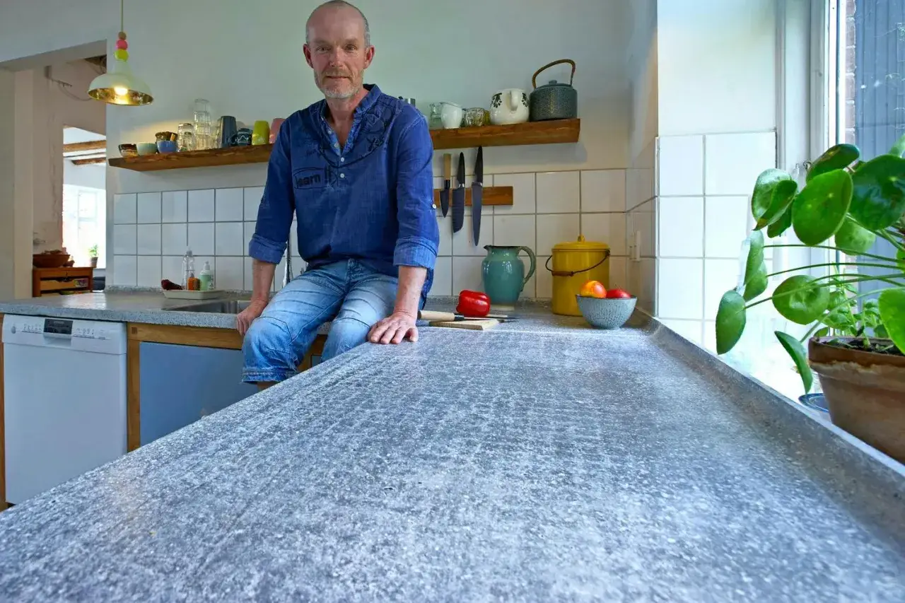 Man sitter p&aring; en k&ouml;ksb&auml;nk med en betongskiva som &auml;r behandlad f&ouml;r att f&aring; en unik yta.