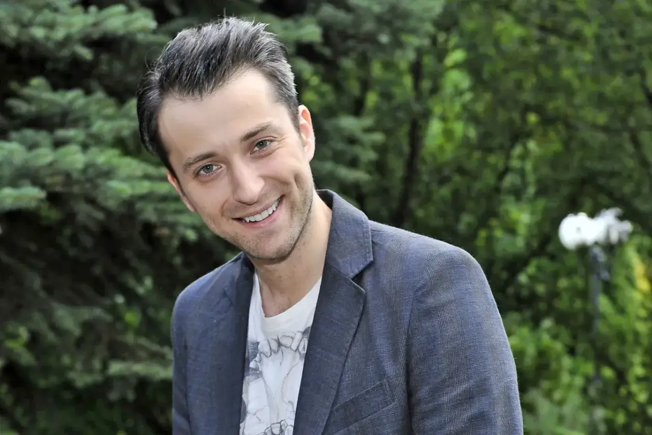 Uśmiechnięty Filip Bobek w marynarce, z dołeczkami w policzkach. Może właśnie myśli o swojej żonie?