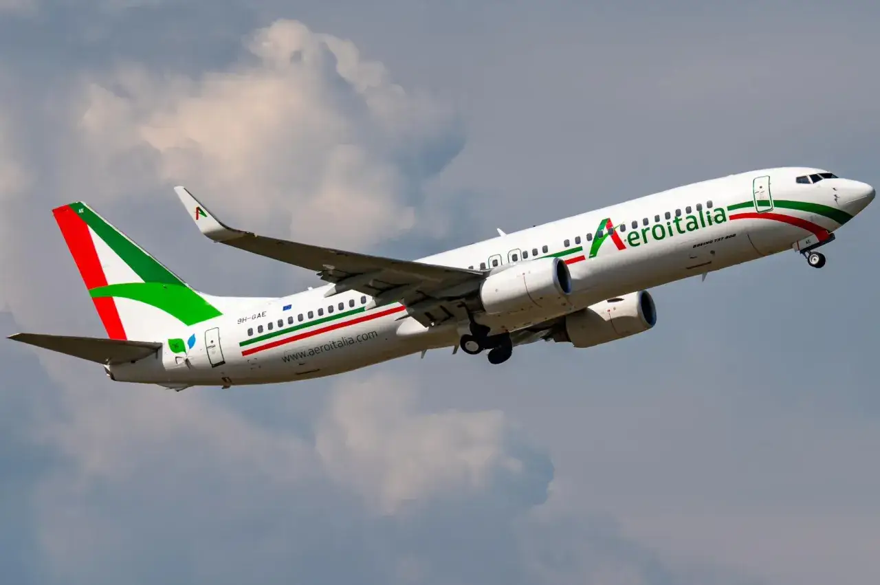 Samolot włoskich linii lotniczych Aeroitalia wznosi się na tle chmur.