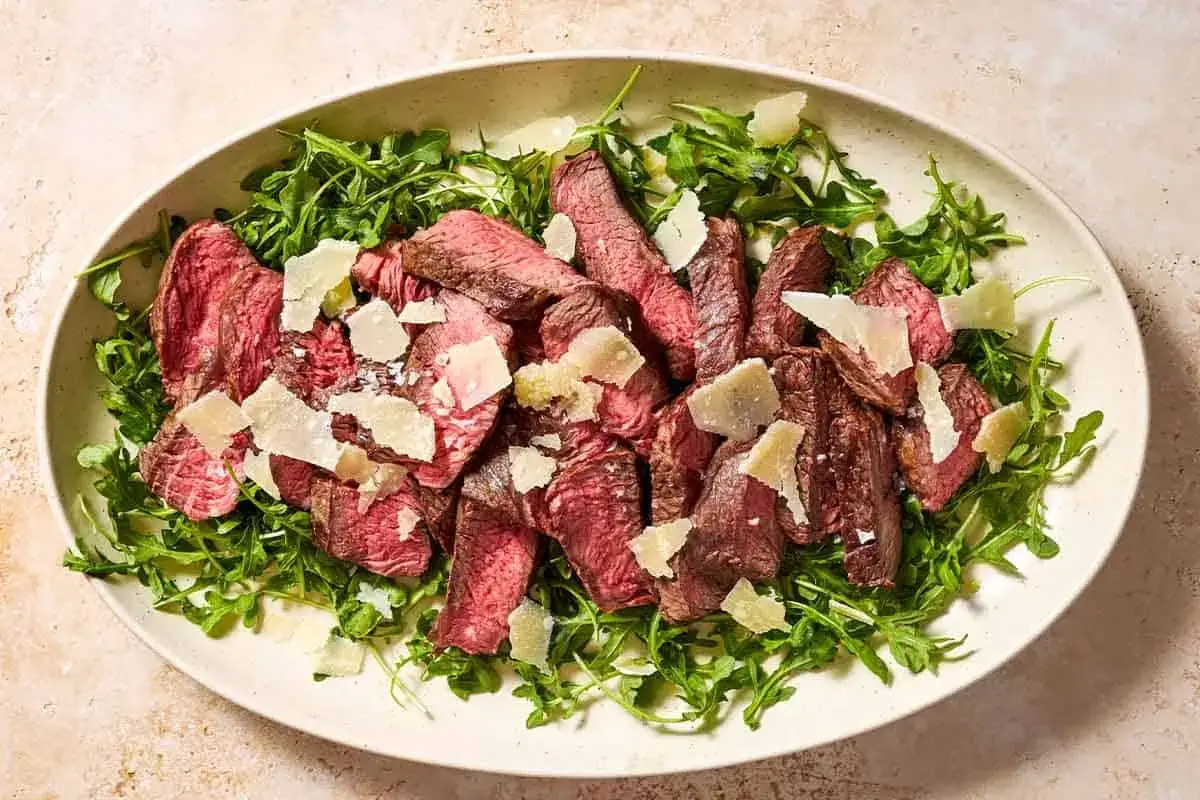 Skivad biff p&aring; en b&auml;dd av rucola, toppad med parmesan. Ett perfekt tagliata recept f&ouml;r en snabb och smakrik middag.