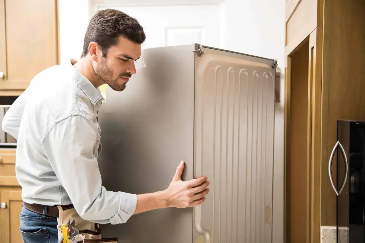 Hombre instalando un refrigerador, uno de los electrodom&eacute;sticos obligatorios en piso de alquiler.