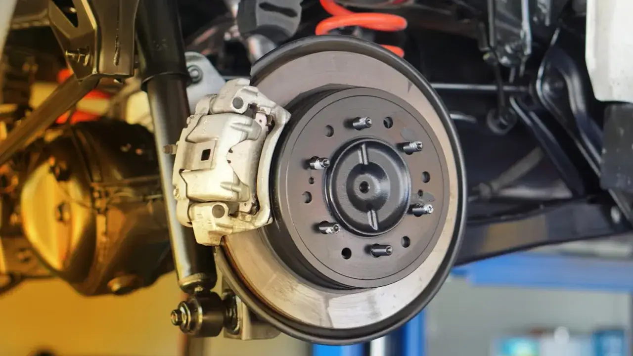 Nahaufnahme einer Autobremsanlage mit Bremssattel und Bremsscheibe. Wichtig für die Sicherheit: die **Bremsscheiben Mindestdicke Tabelle** beachten.