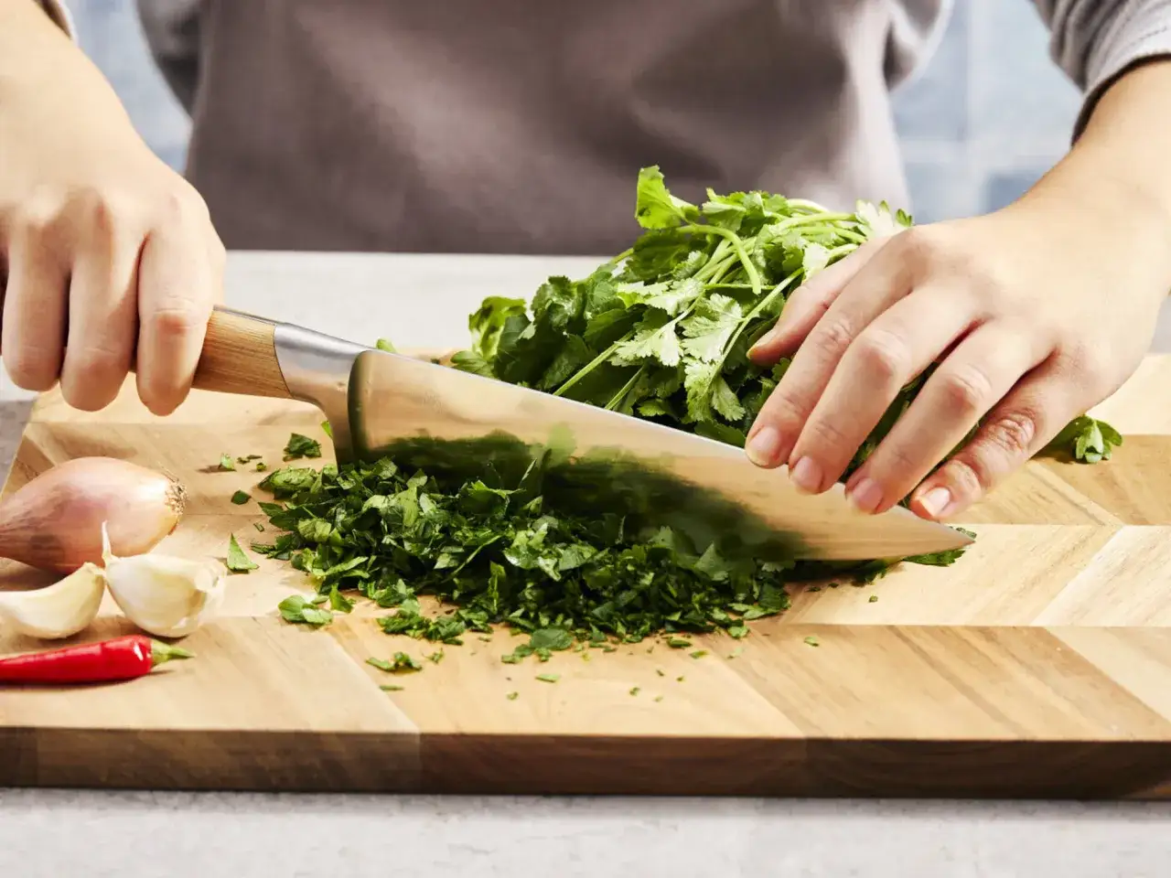 Frische Kr&auml;uter werden gehackt. Wer den **Koriander Geschmack neutralisieren** m&ouml;chte, kann ihn mit anderen Kr&auml;utern mischen. Zwiebel, Knoblauch und Chili liegen bereit.