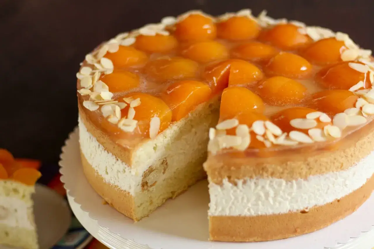 Eine köstliche Windbeutel Torte mit Aprikosen und Mandelsplittern, geschichtet mit Sahne und Biskuit. Ein Genuss für Augen und Gaumen.