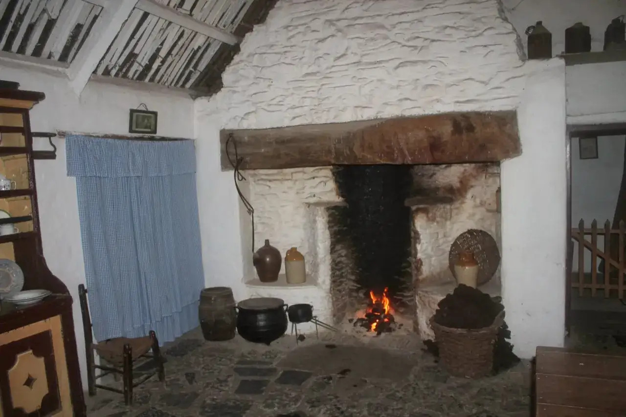 Ein Einblick, wie lebten die Menschen im Mittelalter: Ein Herdfeuer wärmt, daneben ein Kessel und Vorräte.