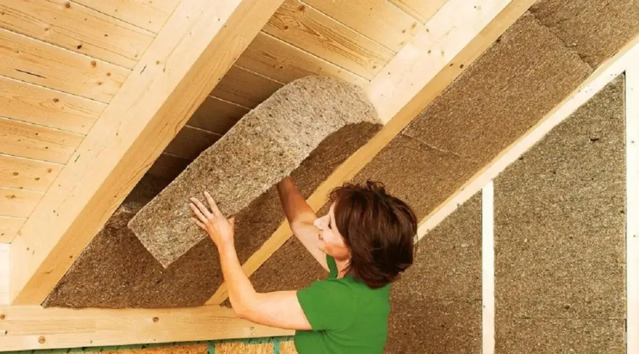 Donna installa pannelli isolanti in fibra di legno, il **miglior isolante termico per soffitto**, per un tetto caldo e confortevole.