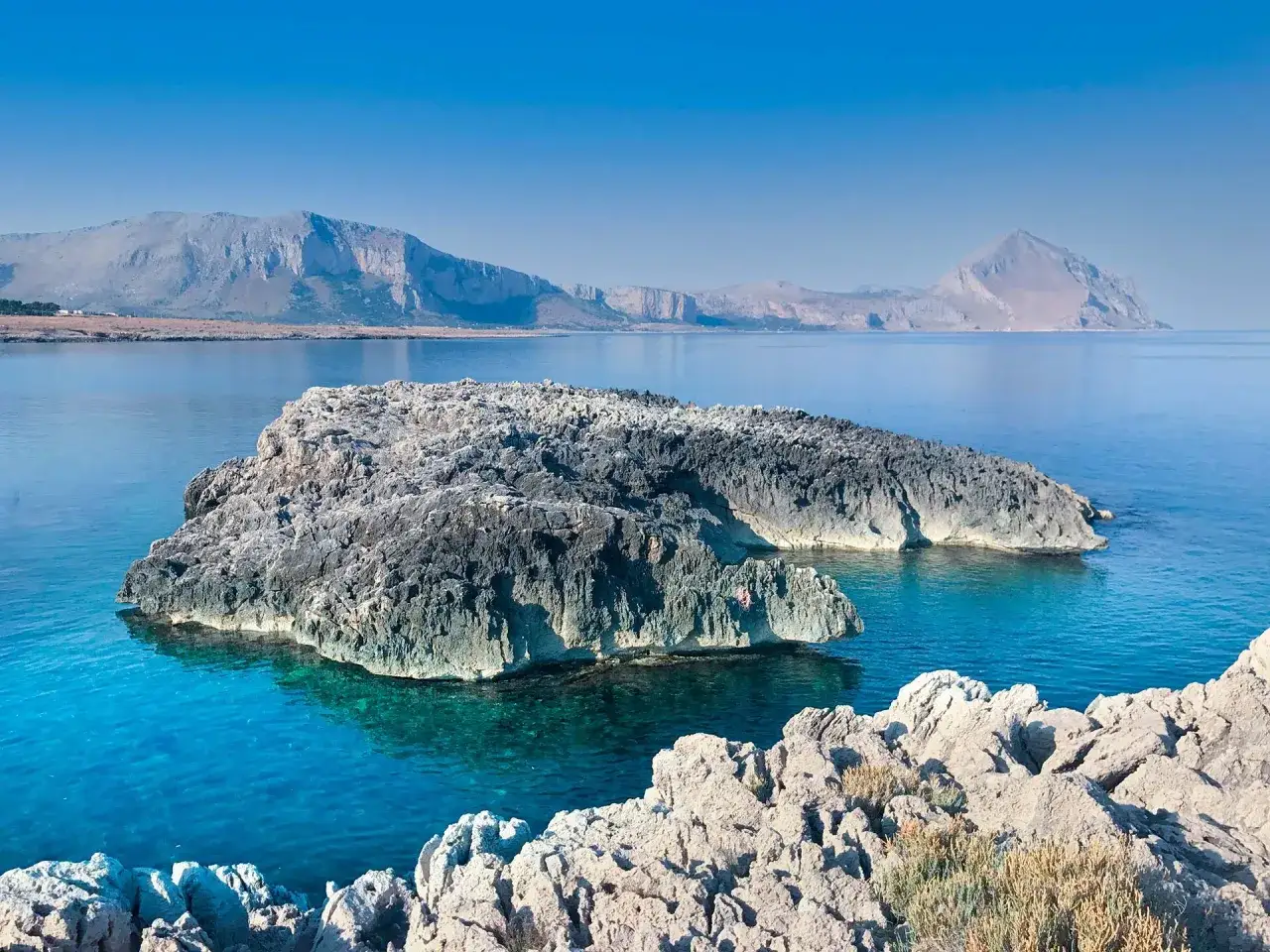 Scogliere rocciose e mare cristallino, un'oasi di pace. San Vito Lo Capo cosa vedere? Questo panorama mozzafiato è solo un assaggio.