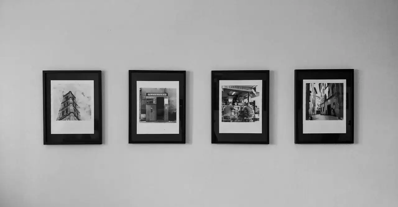 Four framed black and white photographs hang on a wall, showcasing architectural details and street scenes, a collection that feels like a small photography west gallery.