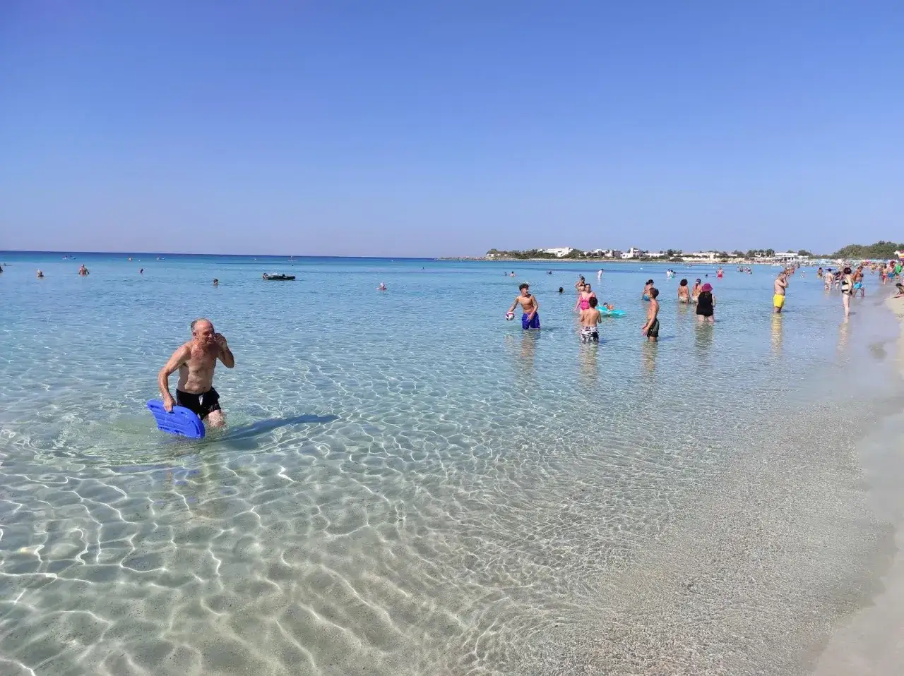 Punta Prosciutto, Maldive del Salento: gente al mare con acqua cristallina e cielo azzurro.