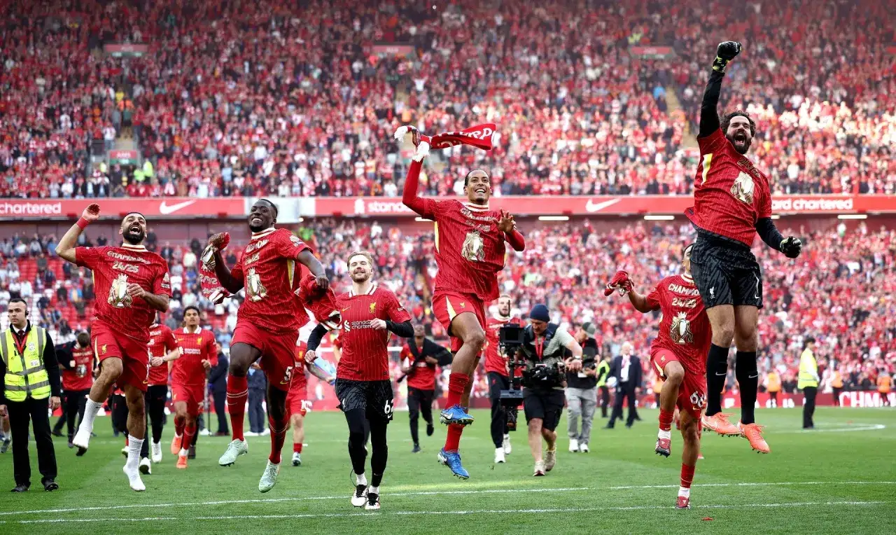 Piłkarze Liverpoolu, mistrzowie Anglii, świętują zwycięstwo na murawie stadionu, otoczeni przez kibiców.