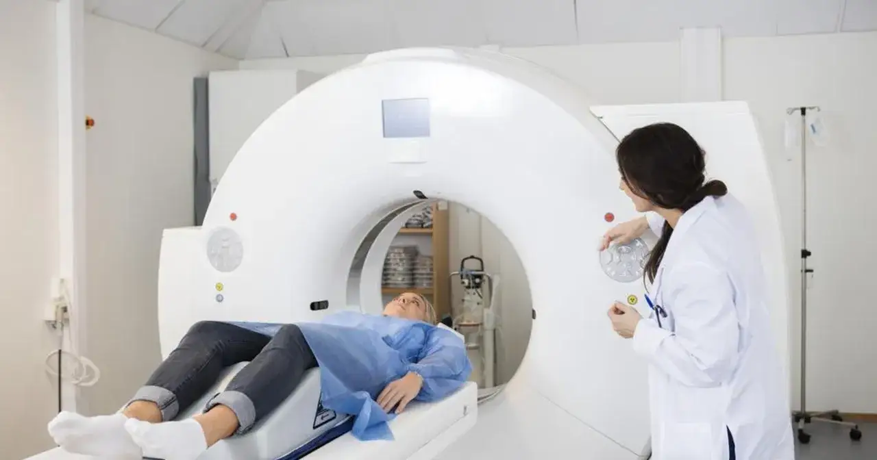 Pacjentka leży na stole tomografu, a lekarka obsługuje urządzenie. To przykład badania, które pomaga odpowiedzieć na pytanie: angiografia co to jest.