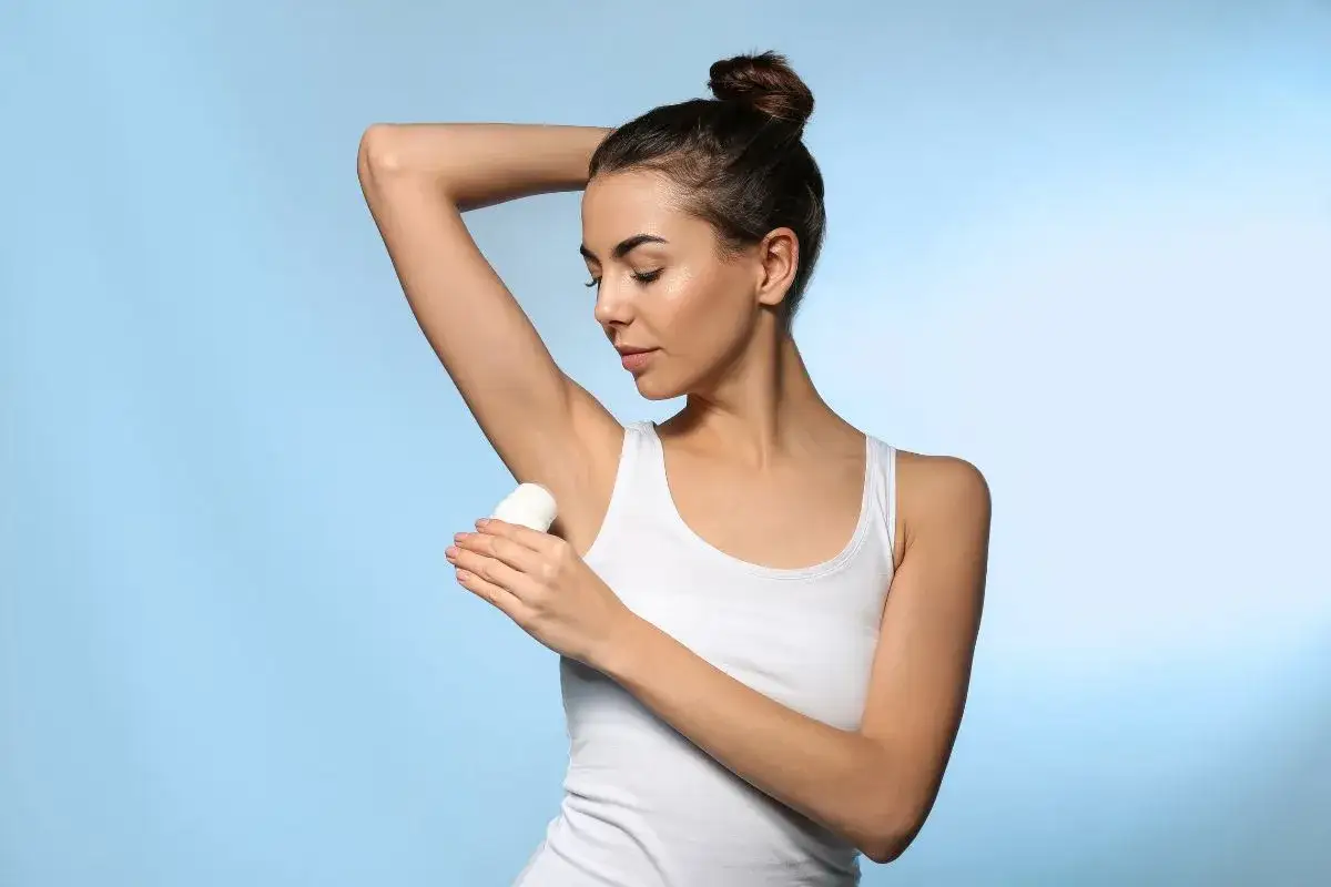 Kobieta aplikuje antyperspirant. Wiele produktów zawiera aluminium, które pomaga ograniczyć potliwość.
