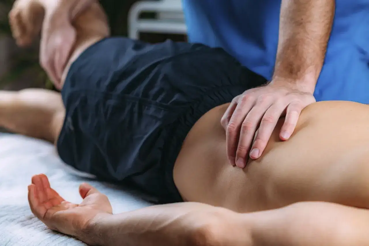Fizjoterapeuta wykonuje terapię manualną dolnej części pleców pacjenta, przynosząc ulgę w bólu.