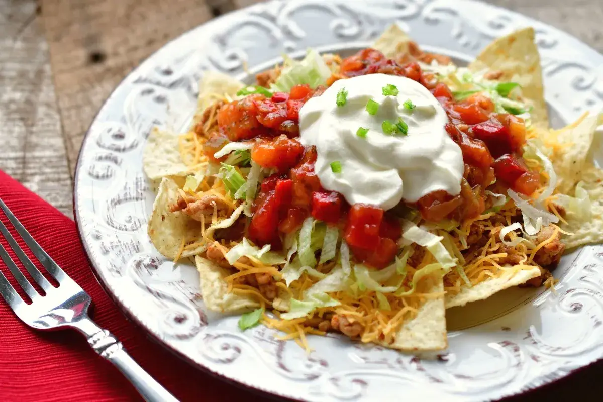 Ein Teller mit einem k&ouml;stlichen Taco Salat, garniert mit saurer Sahne und Salsa.