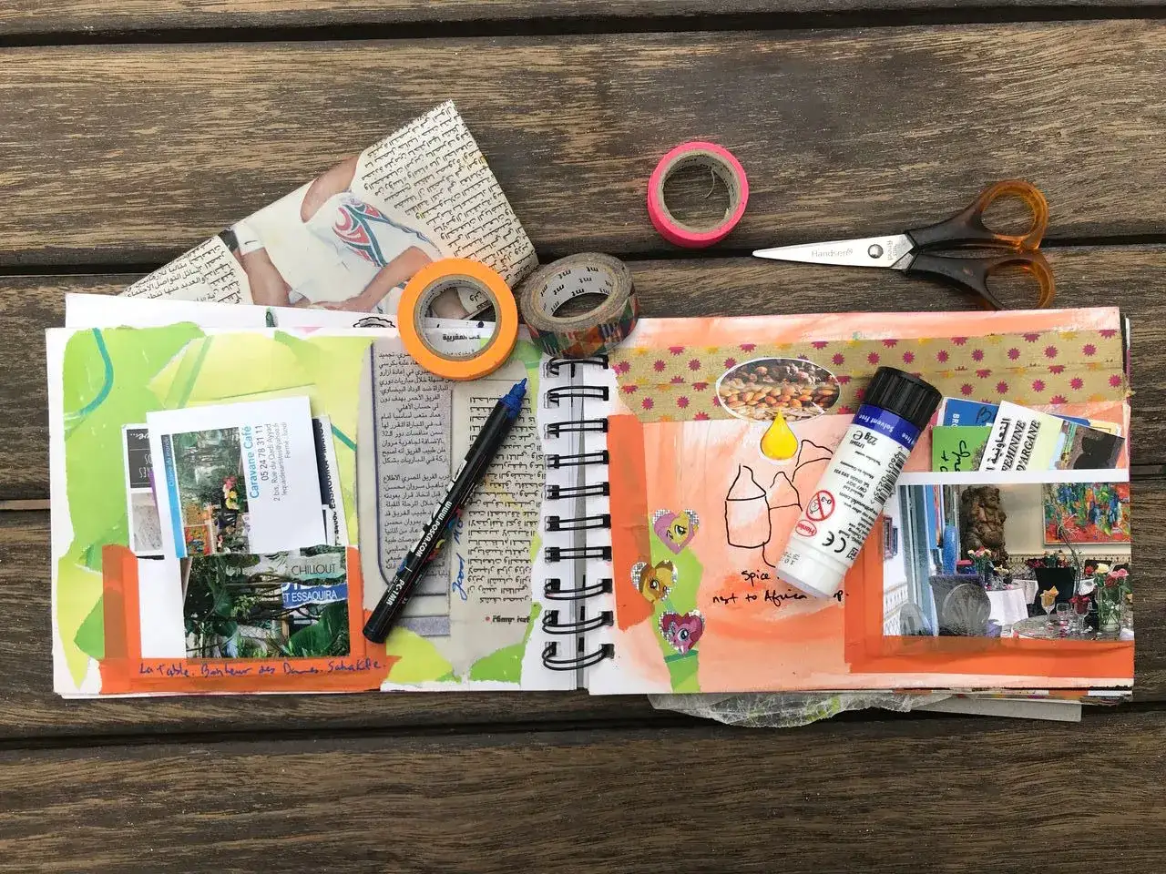 Carnet de voyage en cours de création, avec ciseaux, rubans adhésifs, stylos, photos et collages. Une idée carnet de voyage inspirante.