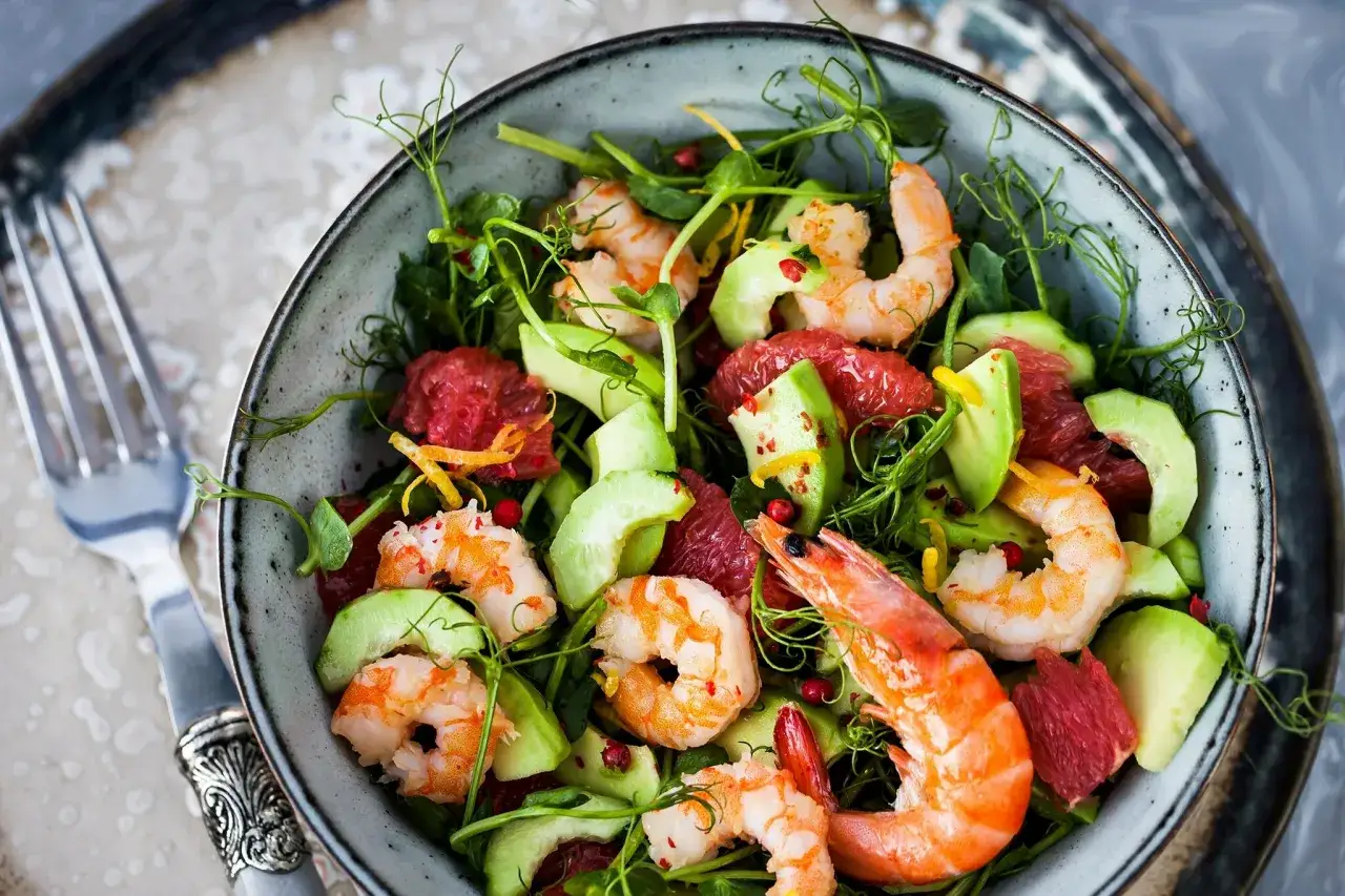 Schüssel mit frischem Salat, Avocado, Grapefruit und den besten Garnelen, garniert mit Sprossen und Zitronenzesten.