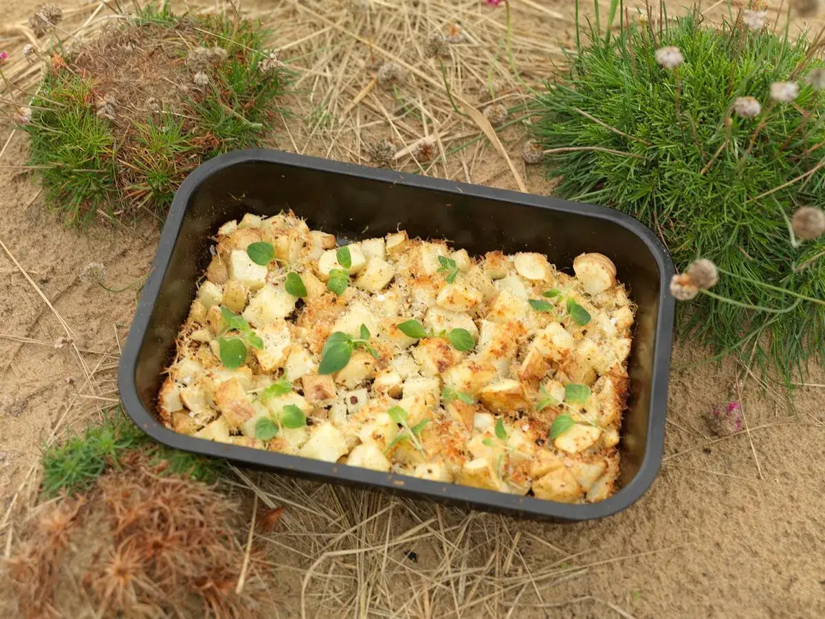 En ugnsform med gyllene, ugnsrostade smashed potatis, toppad med f&auml;rska &ouml;rter. Perfekt f&ouml;r en picknick i det gr&ouml;na.