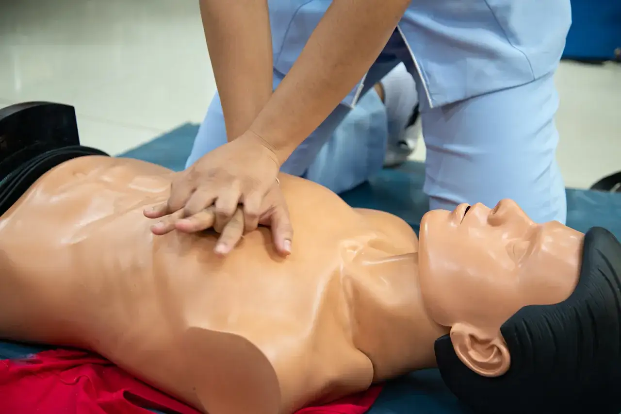 Hände auf die Brust eines Übungspuppen legen, um zu lernen, wie geht herzdruckmassage.