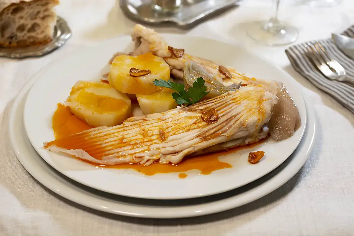 Raya a la gallega con patatas y ajo frito, un plato tradicional gallego servido en un plato blanco.
