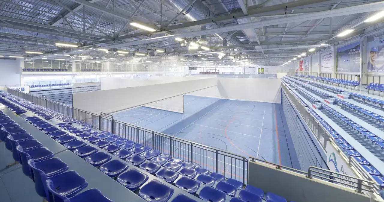 Leere Trib&uuml;nen in der Gummersbach Schwalbe Arena, bereit f&uuml;r spannende Wettk&auml;mpfe auf dem blauen Hallenboden.