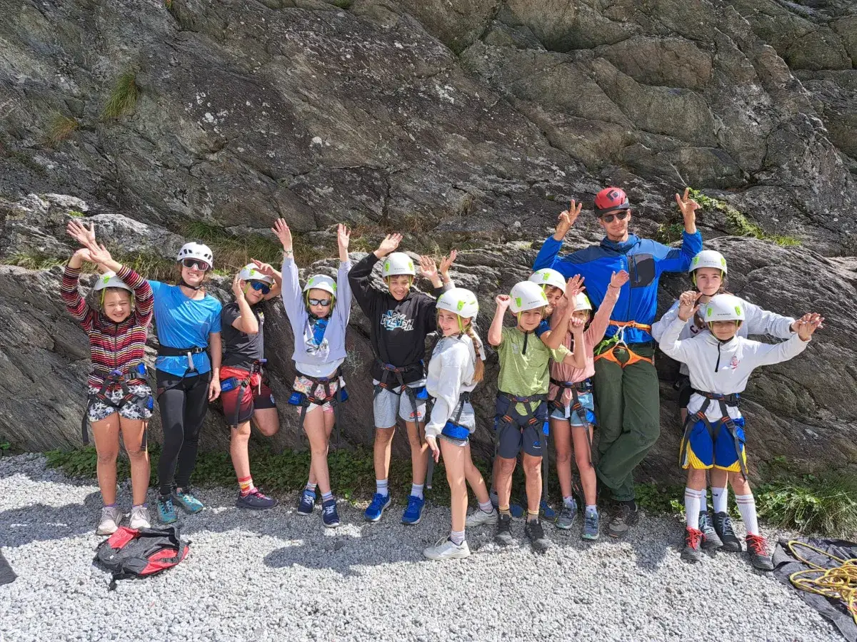 Groupe d'enfants et d'adultes équipés pour l'escalade, prêts pour une aventure dans une colonie des Pyrénées.