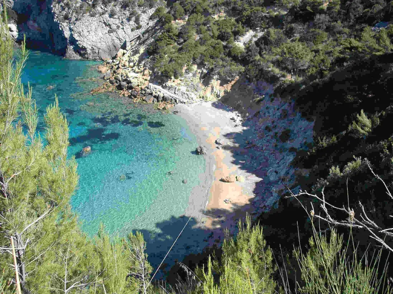Vista dall'alto della cala del gesso spiaggia, con acque cristalline e vegetazione mediterranea.
