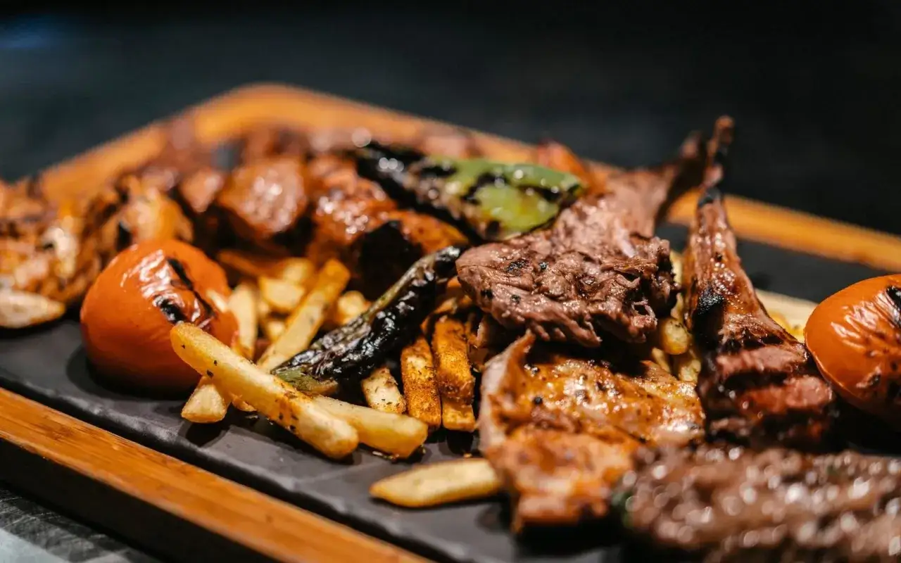 Ein &uuml;ppiger Grillteller mit Lammkoteletts, Steak, H&auml;hnchen, Pommes und gegrillten Tomaten &ndash; ein Festmahl, das man im Hasir Kreuzberg genie&szlig;en kann.