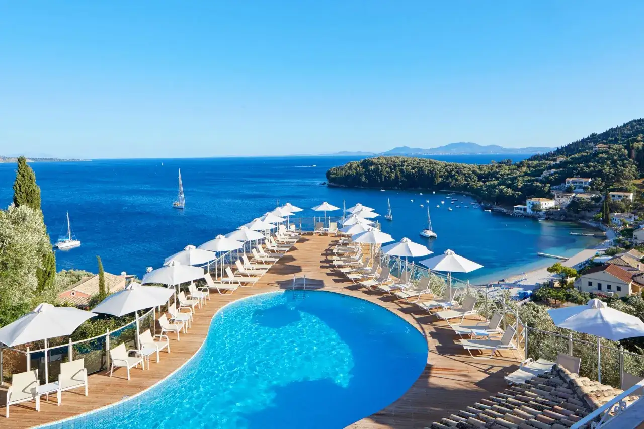 Basen z leżakami i parasolami przy turkusowym morzu. Idealne miejsce na wakacje, zgodnie z opiniami o Messonghi Beach Holiday Resort.