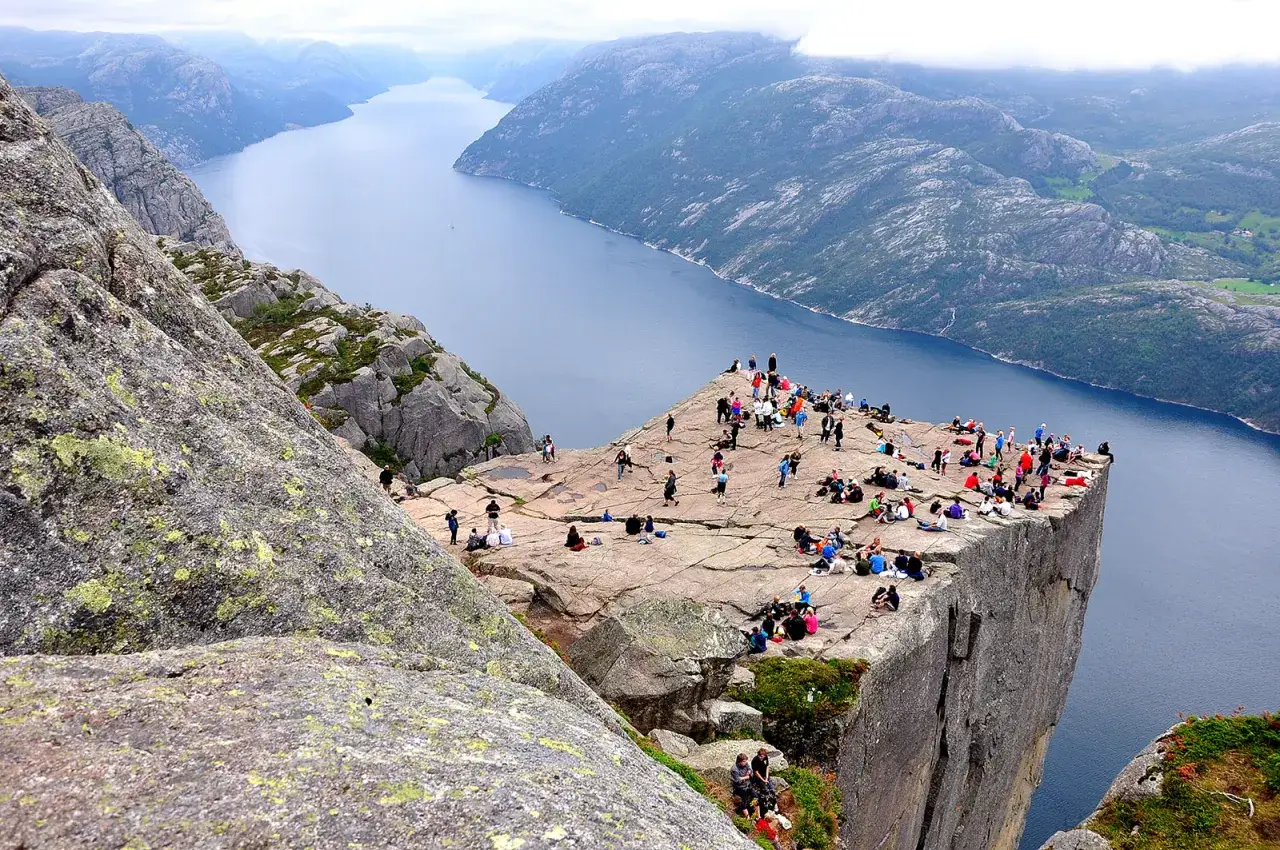 Tłum ludzi na skalnej półce nad fiordami w Stavanger. Widok zapiera dech w piersiach.