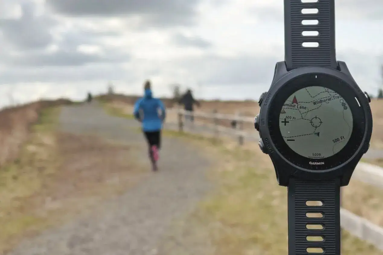 Zegarek Garmin z mapą szlaku, idealny do śledzenia tras w aplikacjach do biegania. W tle biegacz na ścieżce.
