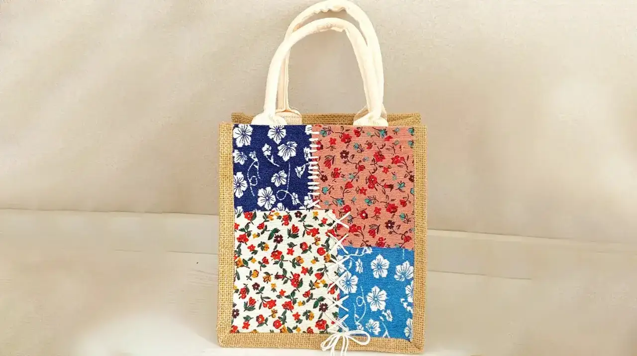 Ein liebevoll bemalter Jutebeutel im Patchwork-Stil mit vier verschiedenen Blumenmustern.