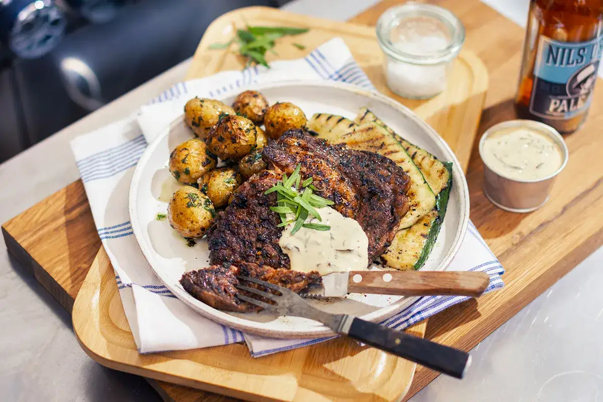 En saftig grillad entrecote med marinad, serverad med krispiga potatisar och grillad zucchini. En perfekt sommarm&aring;ltid.