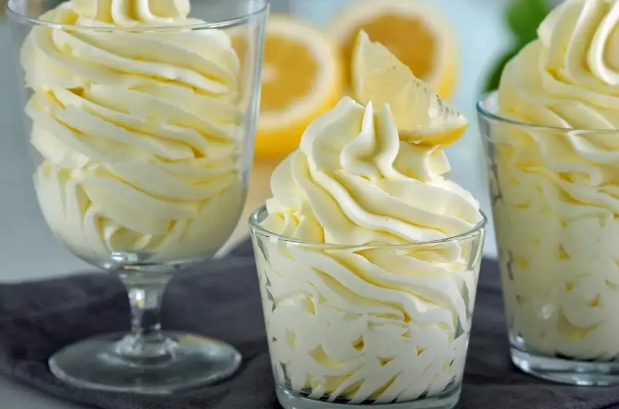 Puszysty krem cytrynowy, przypominający lekki lemon curd, podany w szklanych pucharkach, z plasterkiem cytryny na wierzchu.
