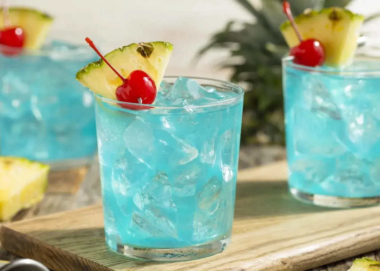 Orzeźwiający drink Blue Hawaii z lodem, ananasem i wisienką. Idealny na wakacje!