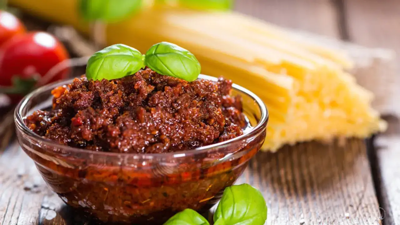 Un invitante pesto di pomodori secchi in una ciotola di vetro, pronto per condire la pasta.