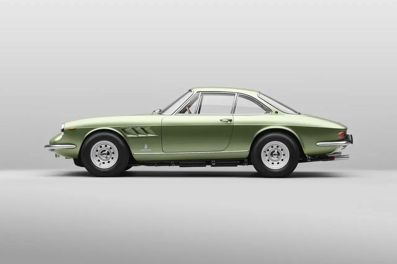 Zielony Ferrari 365 GTB/4 Daytona, klasyk z lat 70., prezentuje swoje eleganckie linie na neutralnym tle.
