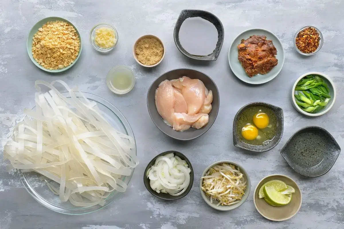 Składniki do pad thai kai: ryżowy makaron, kurczak, jajka, kiełki, cebula, orzeszki ziemne, sosy i przyprawy.