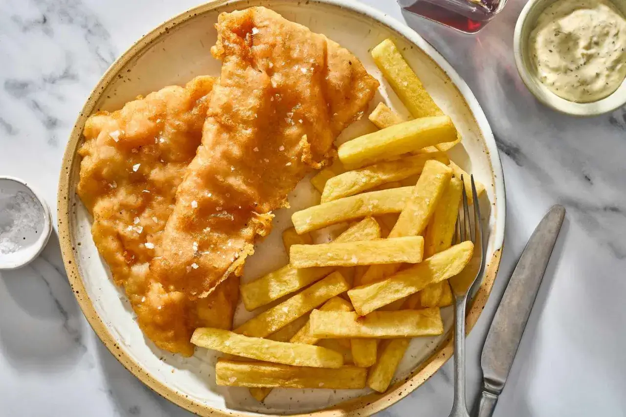 Dos filetes de pescado rebozado y crujiente junto a una generosa porci&oacute;n de patatas fritas doradas. Un cl&aacute;sico fish and chips listo para disfrutar.