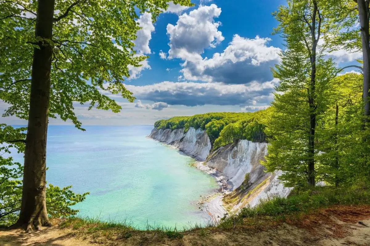 Traumhafter Urlaub im Mai in Deutschland: Kreidefelsen und t&uuml;rkisfarbenes Meer unter blauem Himmel mit Wolken.