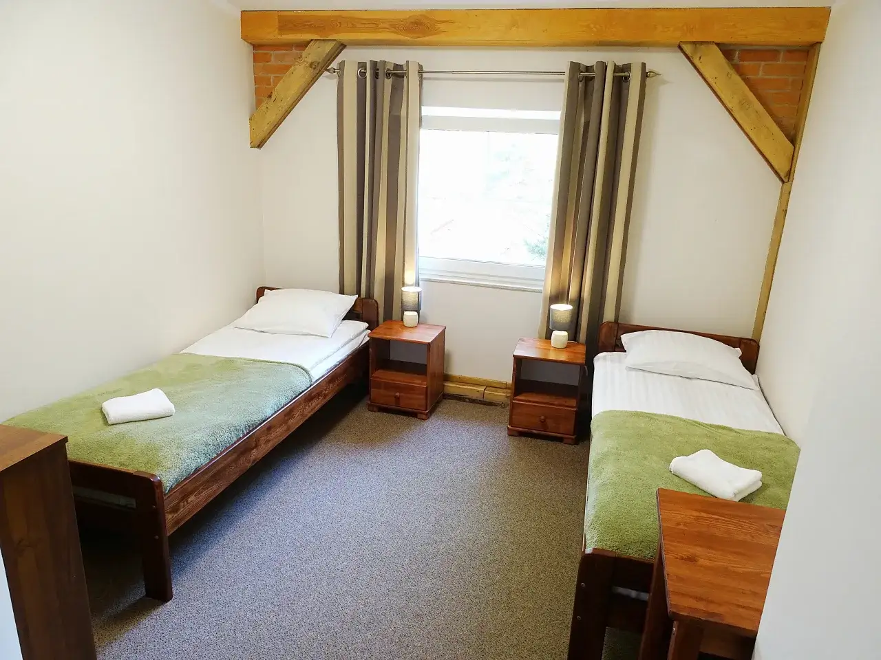 Przytulne pokoje w obiekcie Nowa Fregata Pokoje i Apartamenty. Dwa łóżka z zielonymi narzutami i białymi ręcznikami.